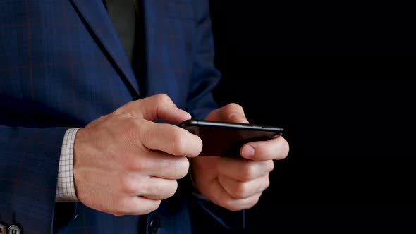 Male Hands Holding a Black Smartphone Close-up. Fingers Touch the Touchscreen of the Phone While