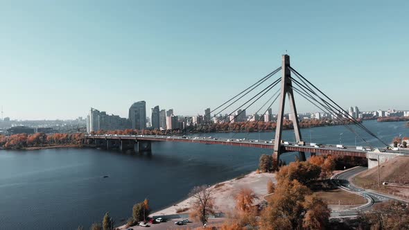 Big concrete bridge with steel rope tows connecting two banks of big metropolis