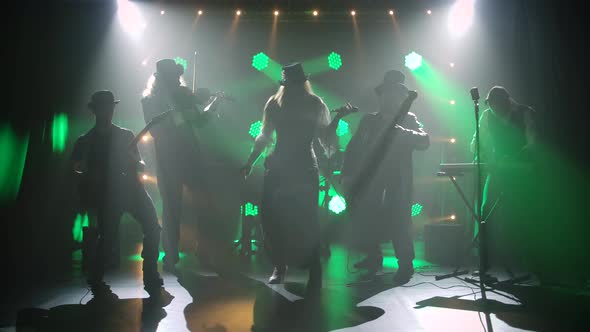 A Group in Vintage Irish Costumes and Hats Perform in a Dark Studio Amid Dynamic Green Lights