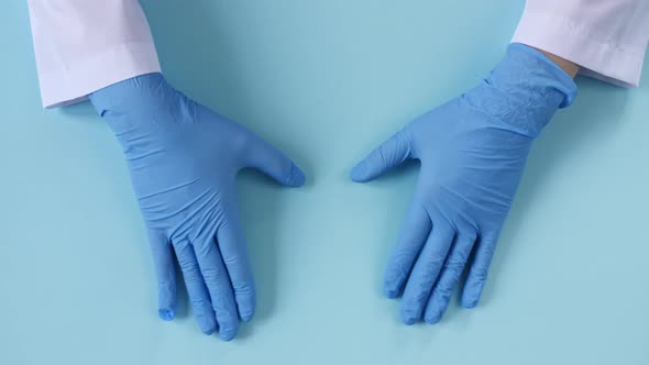 Doctor's Hands in Medical Gloves Shows the Symbol of the Heart on Blue Background with Copy Space