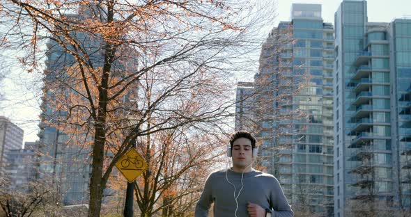 Man listening music while jogging on street 