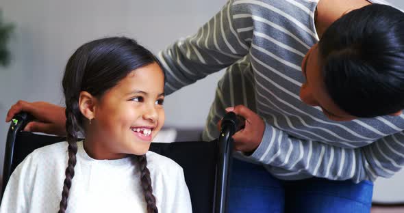 Mother interacting with girl in wheel chair