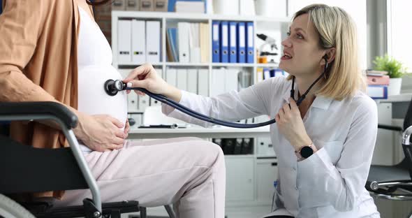 Doctor Listens with Stethoscope to Belly of Pregnant Woman in Wheelchair