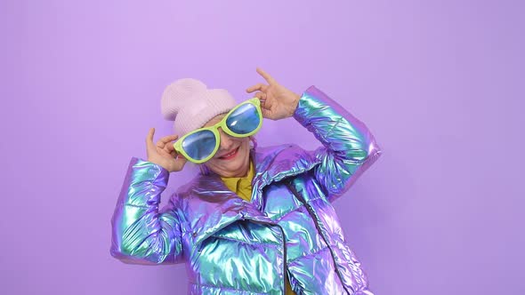 Happy Elderly Woman Tries on Big Funny Glasses Smiling Posing for the Camera in the Studio