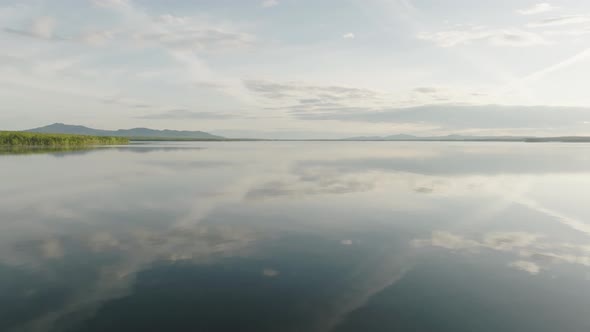 Dreamy flat calm lake reflecting clouds sky Aerial