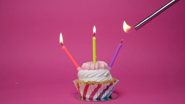 Birthday Cupcake with Candles and Birthday Decorations on Pink Background