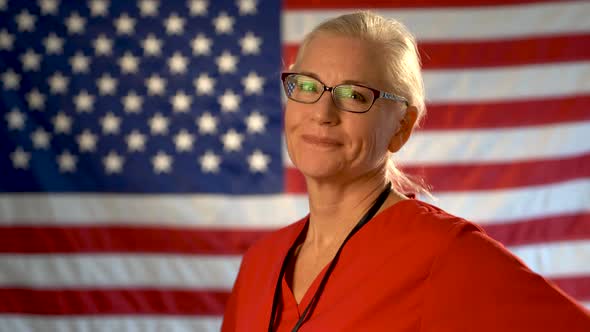 Medium tight portrait of a healthcare nurse turning her head and smiling with out of focus American