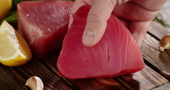 A Man's Hand Puts Raw Tuna Steak on the Table