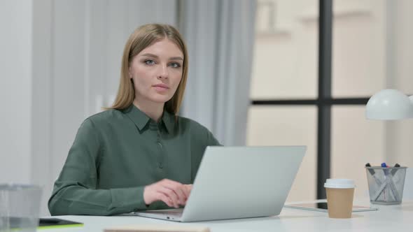 Thumbs Up By Young Woman with Laptop at Work 