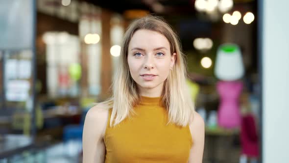 Close-up portrait of a young caucasian blonde woman standing and looking at the camera 
