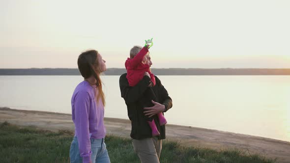 Happy Family Walking with Flying Kite on Field Near Seashore During Sunset Slow Motion