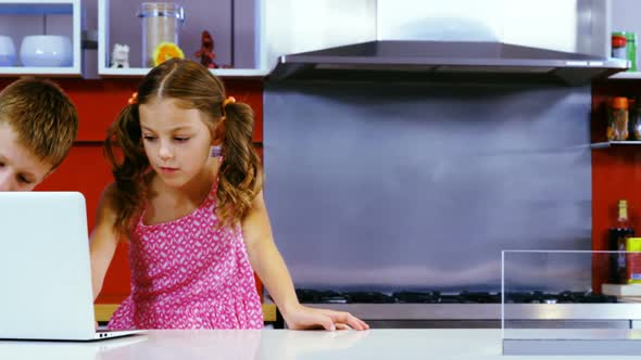 Kids using laptop in kitchen