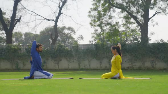 Cow Face Yoga Pose or Gomukh asana is being done by an Indian couple in an Indian outfit