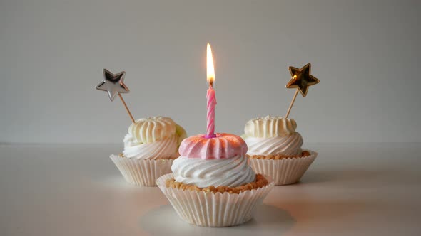 birthday cupcakes with candles and birthday decorations on a light background