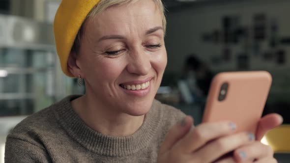 Smiling Mature Woman with Smartphone Resting at Local Cafe