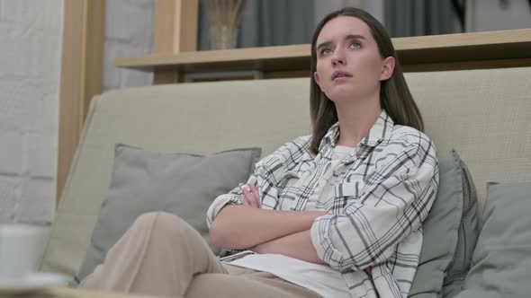 Relaxed Young Woman Sitting on Sofa and Thinking