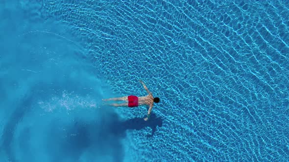 View From the Top As a Man Dives Into the Pool and Swims Under the Water