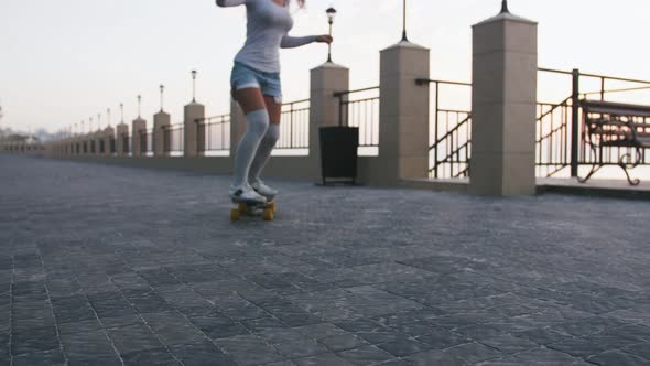 Young Stylish Attractive Woman Skateboarding at Sunrise on Seafront Slow Motion Tracking Shot Close