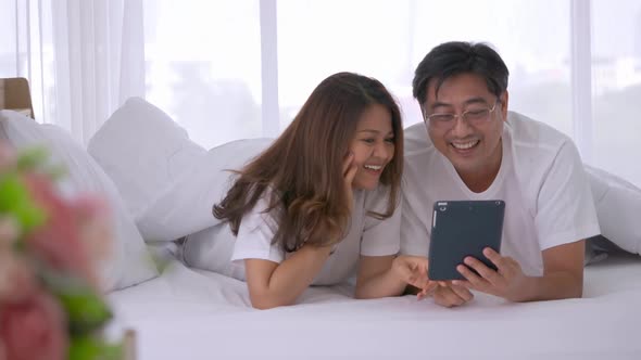 Happy senior couple using tablet computer together on the bed