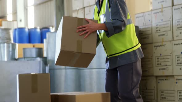 Female worker suffering from back pain while holding heavy box