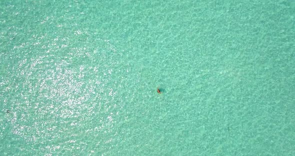 Aerial drone view of a woman floating and swimming on a tropical island