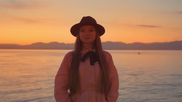 Young Woman in Black Hat Stands Against Lake Garda at Sunset