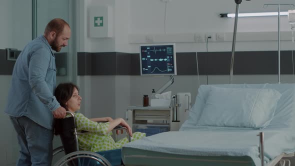 Happy Man Assisting Pregnant Wife with Wheelchair