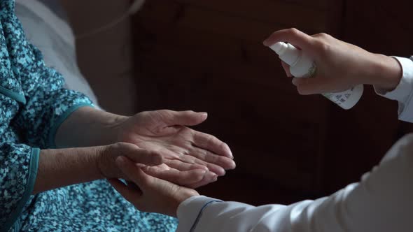 Medic Disinfects Elderly Woman's Hands with Spray Prevention of Coronavirus Infection