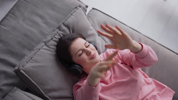 Woman Relaxing on Comfortable Sofa with Eyes Closed Wearing Headphones