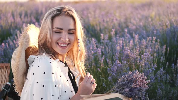 Pretty Blond Woman in a Dress Sitting in the Lavender Field