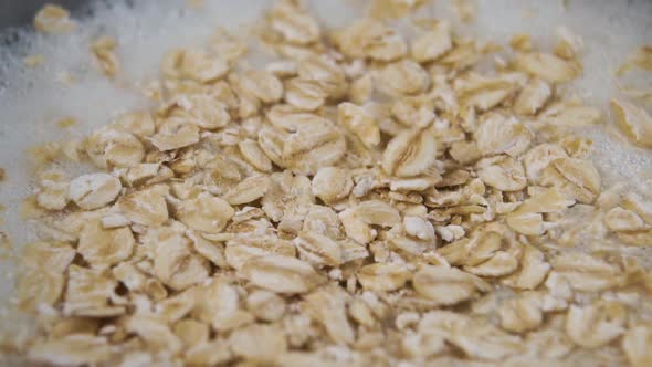 Oatmeal falls into a bowl of fresh milk in slow motion to make breakfast cereal