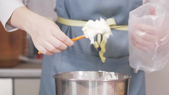 Closeup of a Pastry Chef Filling a Pastry Bag with White Cream