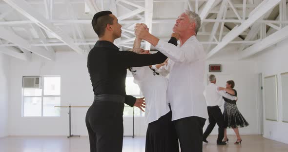 mixed race male dance teacher taking a ballroom dancing class at a dance studio