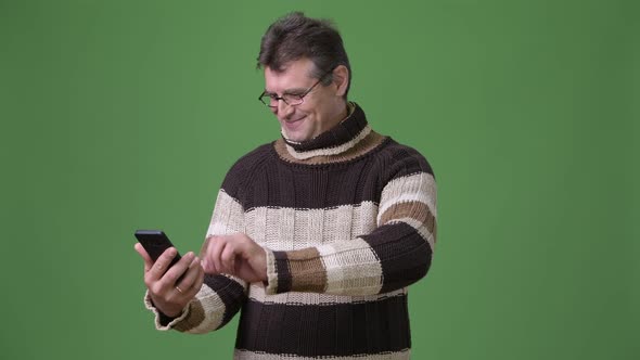 Mature Handsome Man Wearing Turtleneck Sweater Against Green Background