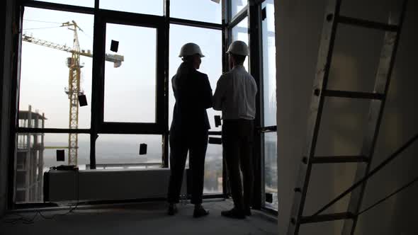 Two Architects Looking at Cityscape Outside Window