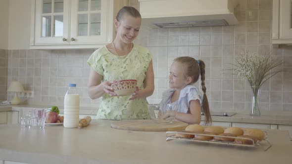 Beautiful Young Mother and Little Cute Daughter Cook in the Kitchen Together