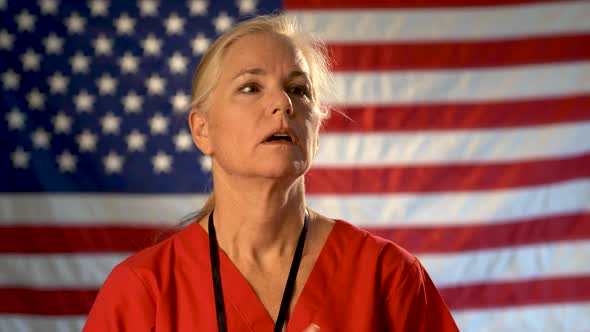 Medium tight portrait of nurse looking relieved, happy and nodding her head with American flag behin