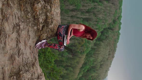 Girl Blogger Traveler is Typing Text on Laptop While Sitting on Top Mountain