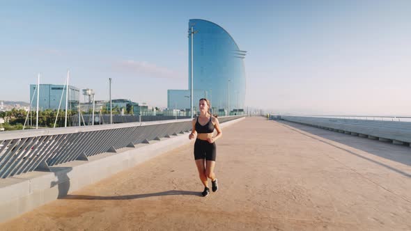 Sportswoman Running on Embankment in Morning