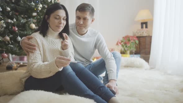 Upset Couple Looking at Negative Pregnancy Test Result and Sighing