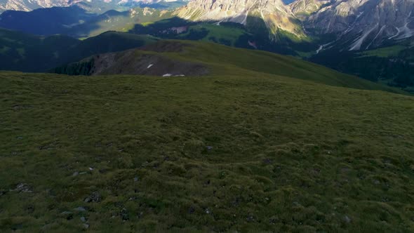 Grassland meadow aerial view revealing solitary South Tyrol Peitlerkofel sunlit mountain peak