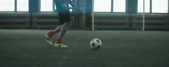 Football Athlete Dribbling Ball on Indoor Field