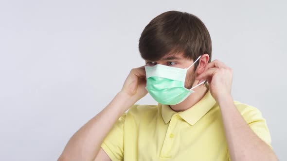 Happy Man Putting on Disposable Sterile Mask To Protect His Face and Shows Thumbs Up To Camera