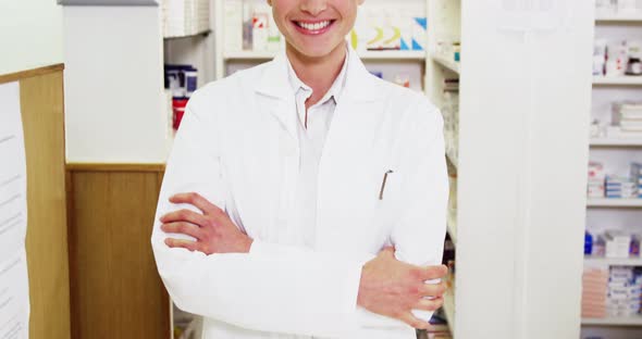 Pharmacist standing with arms crossed in pharmacy