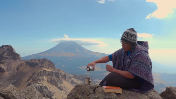 Man sitting outside on rocks  holding a book and looking the landscape