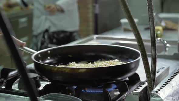 Chef is Making Flambe Sauce on Restaurant Kitchen with Onion and Wine