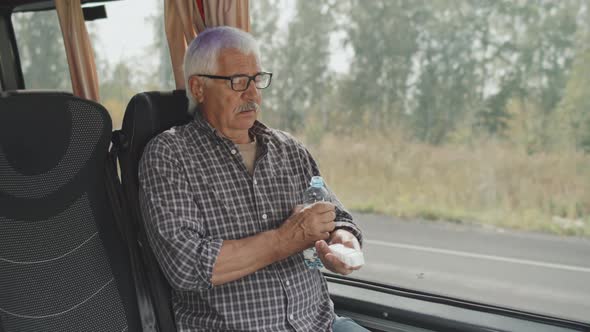 Senior Man Taking Medicines in Bus