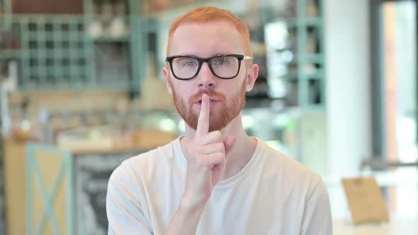Portrait of Young Redhead Man with Finger on Lips Quiet