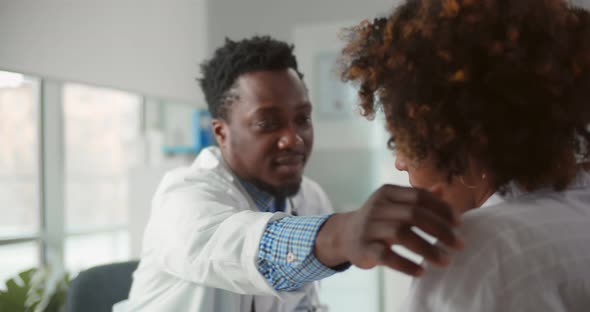 Caring African Medical Specialist Comforting Young Woman Patient in Office