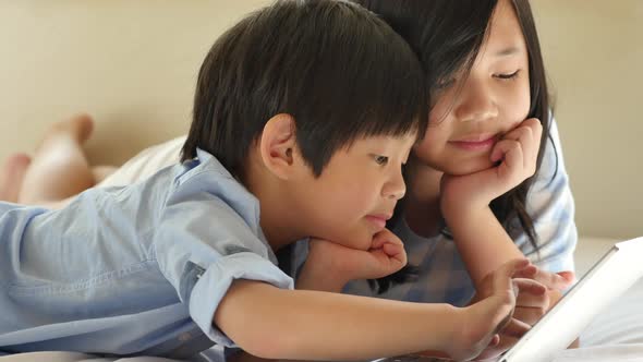 Cute Asian Children  Lying In Bed And Using Laptop On White Bed